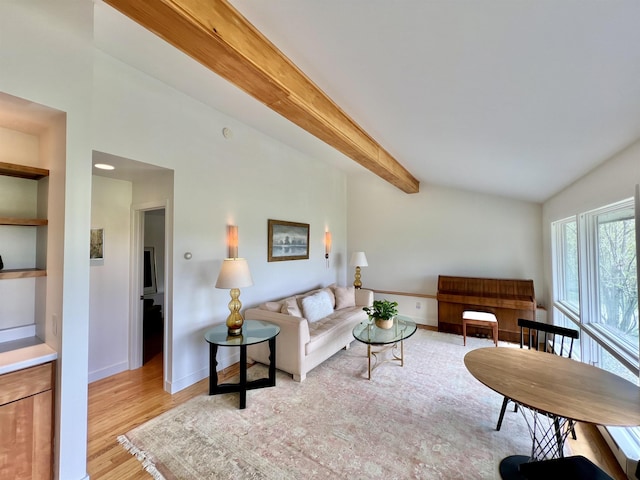 living room featuring baseboards, light wood finished floors, beam ceiling, and built in features