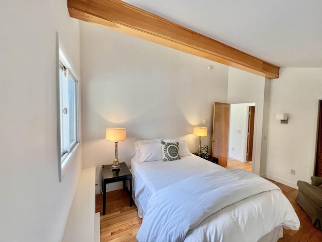 bedroom with lofted ceiling with beams, baseboards, and light wood-style floors