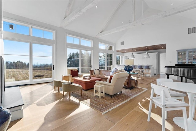 living area featuring beamed ceiling, visible vents, light wood-style flooring, and high vaulted ceiling