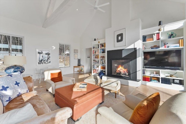 living area with a ceiling fan, a multi sided fireplace, beamed ceiling, and high vaulted ceiling