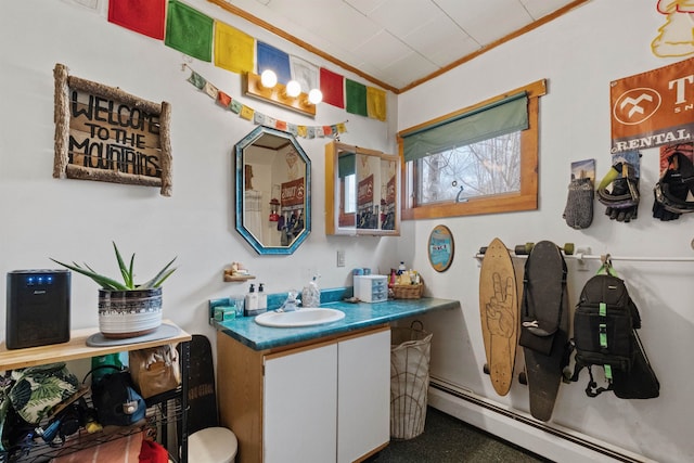 bathroom featuring crown molding, a baseboard heating unit, and vanity