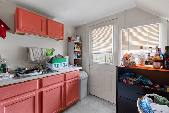 kitchen featuring vaulted ceiling, light tile floors, and sink