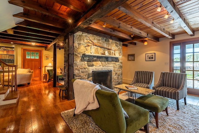 living room with wood-type flooring, beamed ceiling, a fireplace, and wooden ceiling