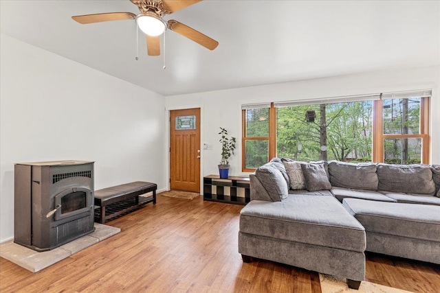 living room with ceiling fan, a wood stove, and light wood-type flooring