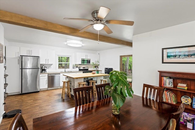 dining space featuring ceiling fan, beam ceiling, dark hardwood / wood-style flooring, and sink