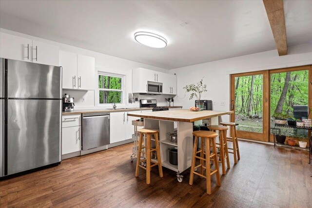 kitchen featuring appliances with stainless steel finishes, beam ceiling, dark hardwood / wood-style flooring, and white cabinets