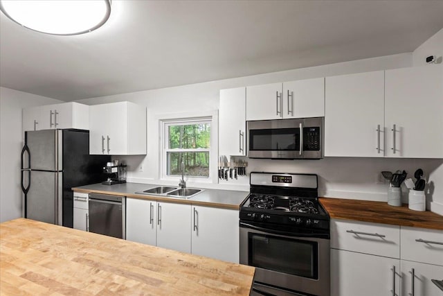 kitchen with butcher block counters, sink, white cabinetry, and stainless steel appliances