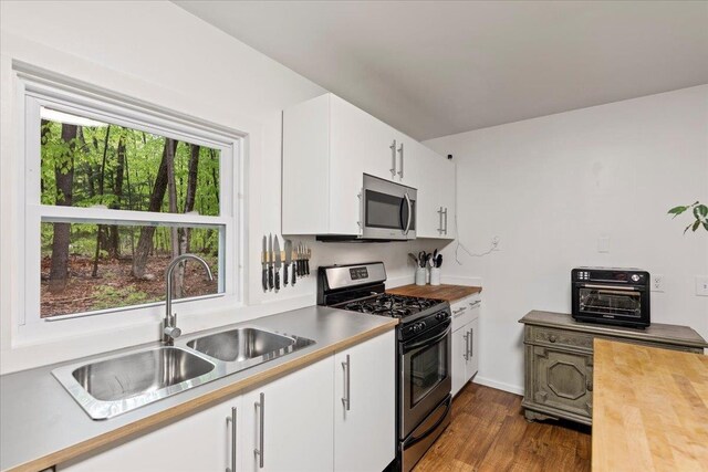 kitchen featuring appliances with stainless steel finishes, dark hardwood / wood-style floors, sink, and white cabinets