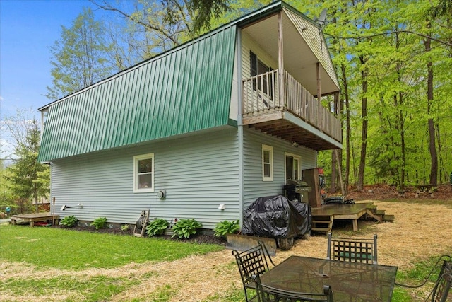 rear view of property with a balcony and a lawn