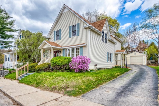 view of front of home featuring a garage, an outbuilding, a front lawn, and aphalt driveway