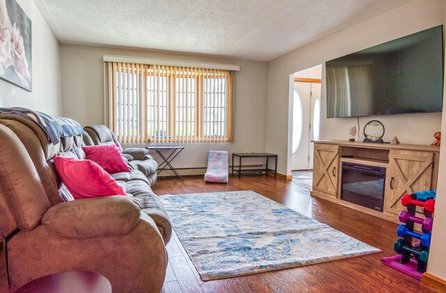 living room with a baseboard heating unit, a textured ceiling, and dark wood-type flooring