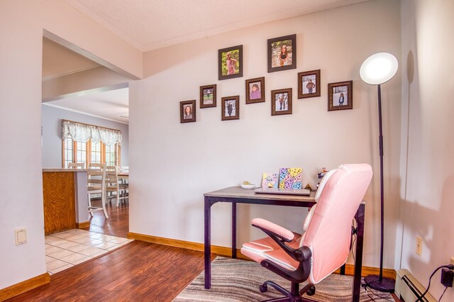 office space with a baseboard heating unit, hardwood / wood-style flooring, and a textured ceiling