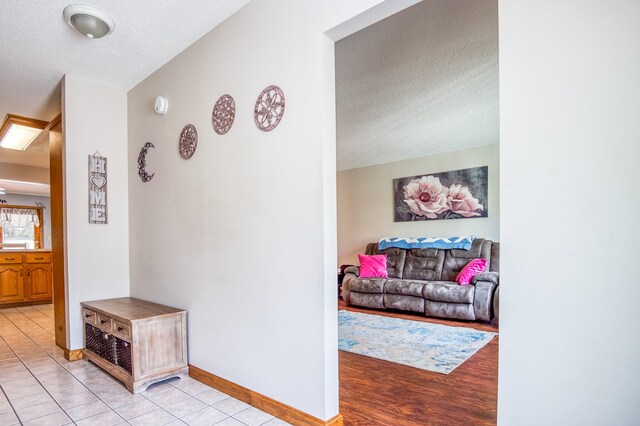 hallway with a textured ceiling and light tile floors