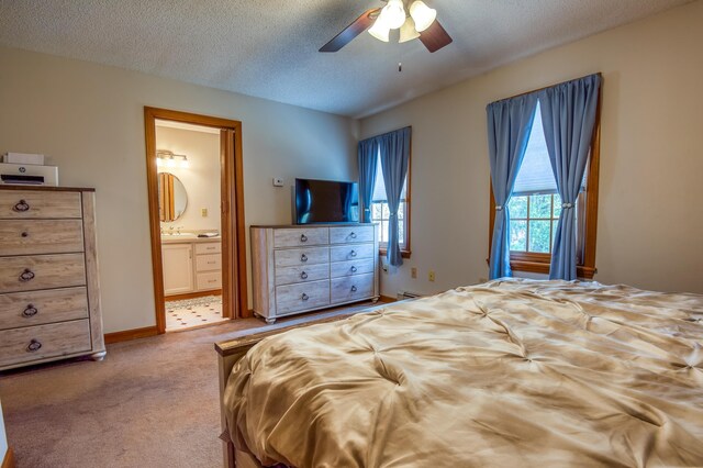 bedroom with carpet, ceiling fan, a textured ceiling, and connected bathroom