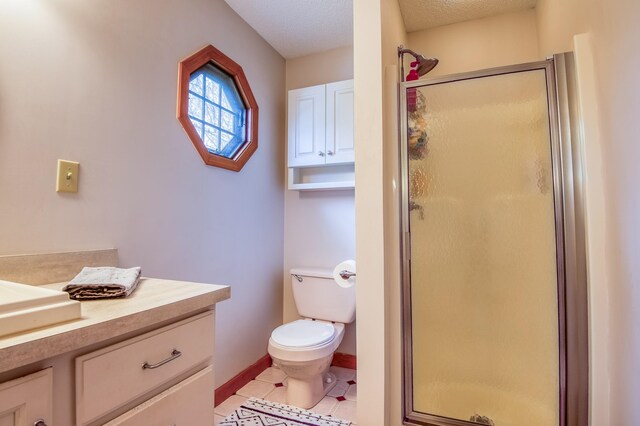 bathroom with tile floors, a shower with shower door, toilet, and vanity