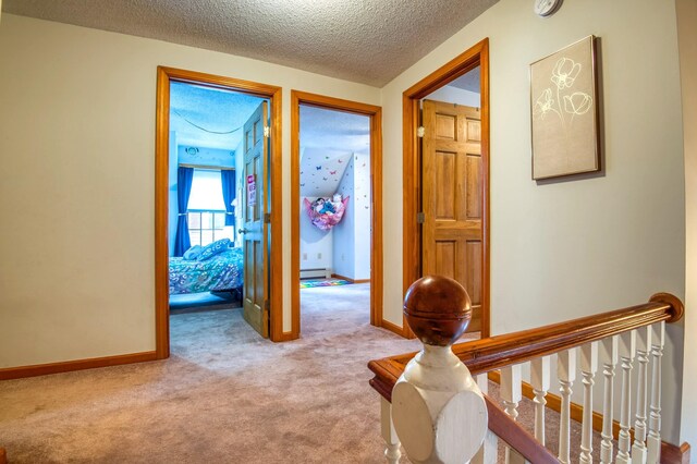 corridor with carpet flooring, a baseboard radiator, and a textured ceiling