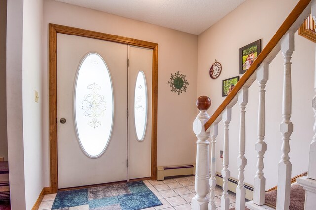 foyer with a baseboard heating unit, a textured ceiling, and light tile flooring