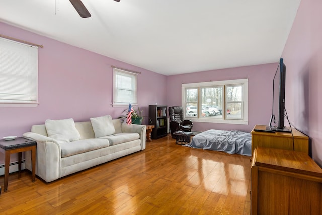 bedroom with baseboard heating, hardwood / wood-style floors, and ceiling fan