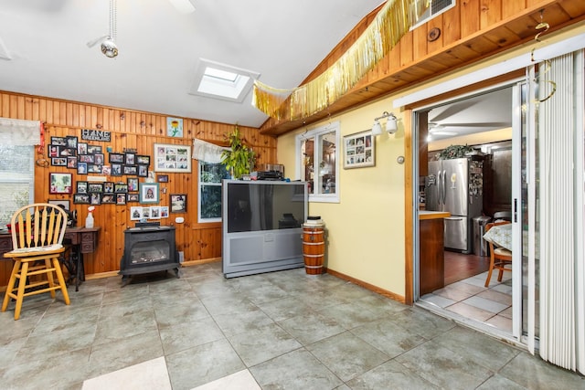 kitchen featuring tile floors, ceiling fan, stainless steel fridge, and a wood stove