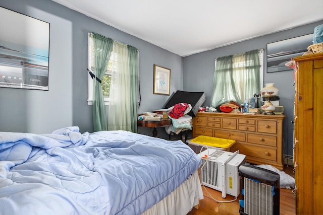 bedroom with hardwood / wood-style floors and a baseboard radiator