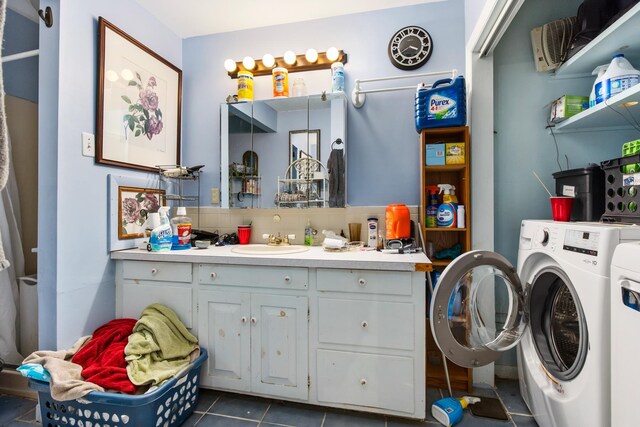 washroom featuring washer and clothes dryer, sink, and dark tile floors