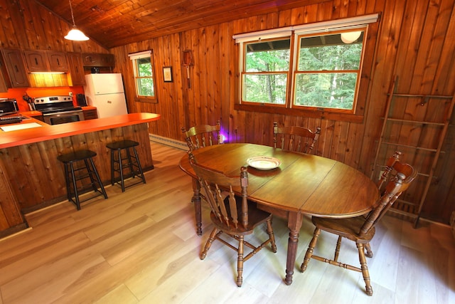 dining room featuring light wood-type flooring, wooden walls, and a baseboard heating unit