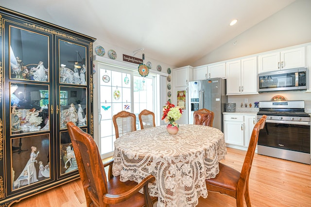 dining area with vaulted ceiling and light wood-type flooring