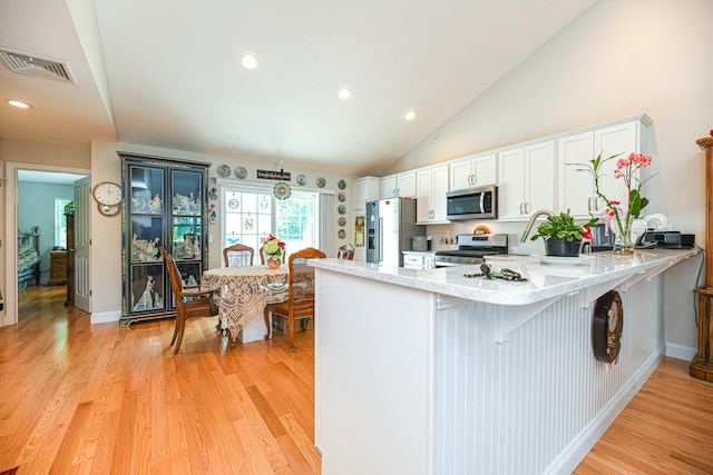 kitchen featuring white cabinets, light wood-type flooring, kitchen peninsula, and appliances with stainless steel finishes