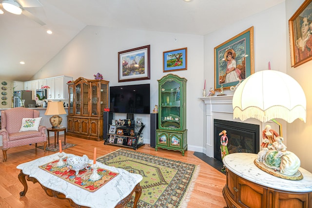 living room featuring ceiling fan, light hardwood / wood-style floors, and lofted ceiling