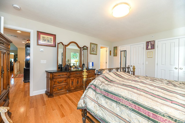 bedroom featuring multiple closets, light hardwood / wood-style floors, and a textured ceiling