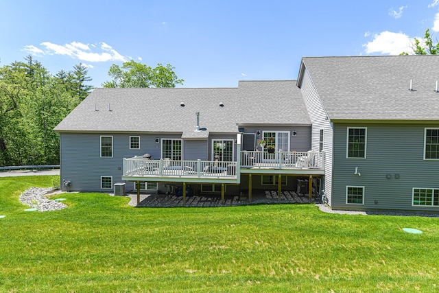 rear view of property featuring a yard, a wooden deck, and central AC