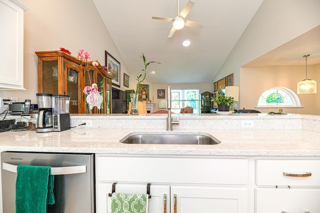 kitchen featuring white cabinets, vaulted ceiling, stainless steel dishwasher, and light stone counters