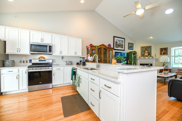 kitchen with sink, kitchen peninsula, stainless steel appliances, and light wood-type flooring