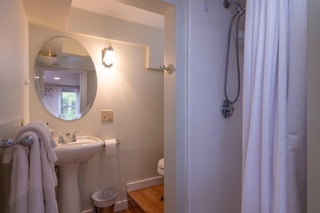 bathroom with curtained shower, wood-type flooring, and toilet