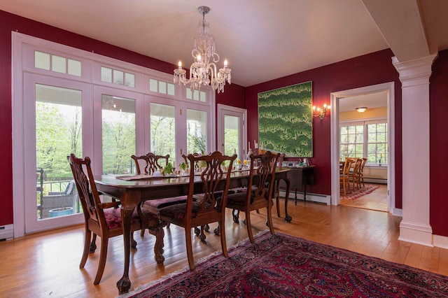 dining area with a baseboard heating unit, light hardwood / wood-style flooring, a notable chandelier, and ornate columns