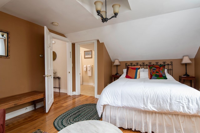 bedroom with a chandelier, vaulted ceiling, and hardwood / wood-style flooring