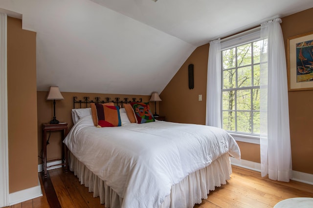 bedroom with hardwood / wood-style floors and lofted ceiling