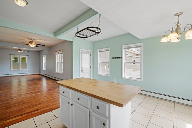 kitchen featuring hanging light fixtures, white cabinets, light hardwood / wood-style flooring, wooden counters, and a kitchen island