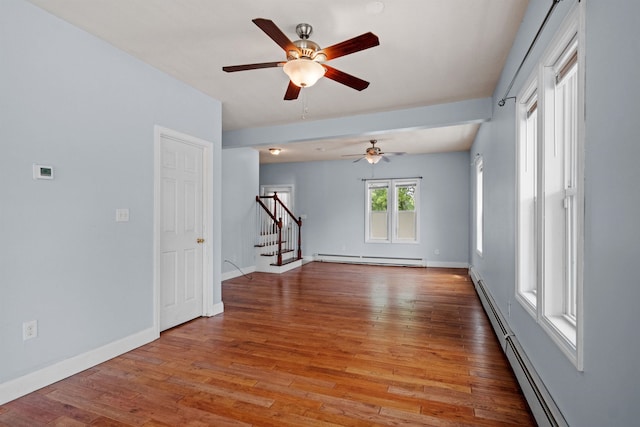 unfurnished room with ceiling fan, light wood-type flooring, and a baseboard heating unit