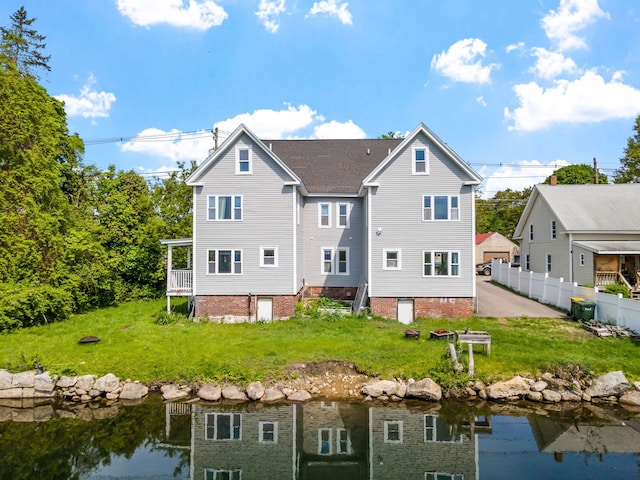 rear view of property with a water view and a yard