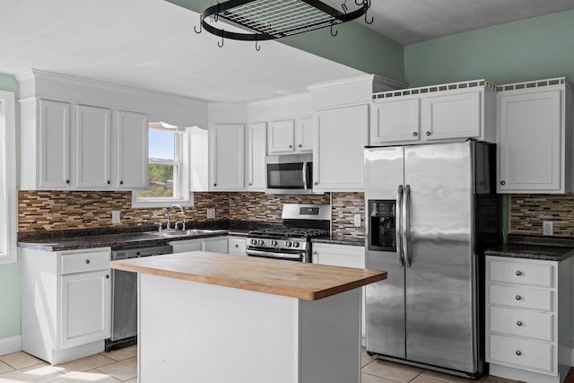 kitchen with a kitchen island, tasteful backsplash, wooden counters, white cabinets, and appliances with stainless steel finishes