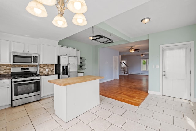 kitchen featuring light wood-type flooring, stainless steel appliances, white cabinets, a center island, and butcher block counters