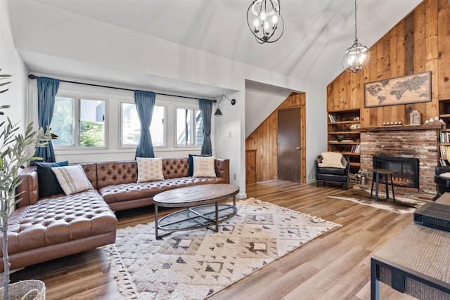 living room with a notable chandelier, a fireplace, wooden walls, and hardwood / wood-style floors