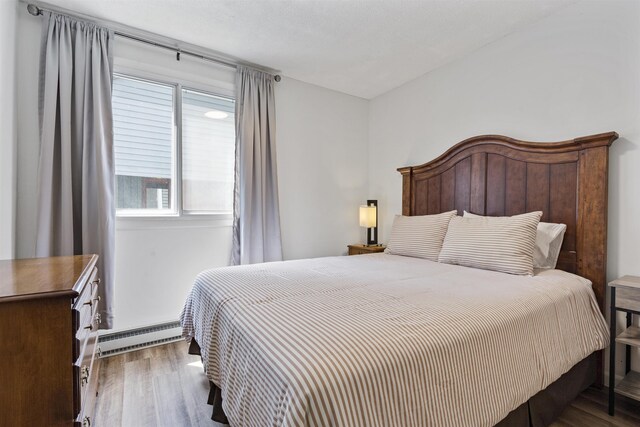 bedroom featuring hardwood / wood-style floors and baseboard heating