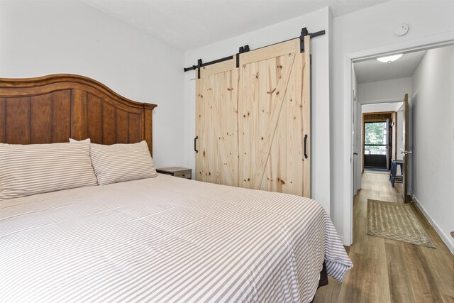 bedroom with a barn door and wood-type flooring