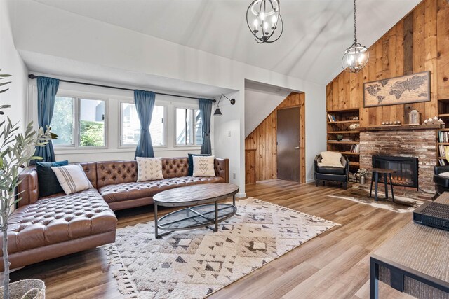 living room with hardwood / wood-style flooring, a brick fireplace, wood walls, and an inviting chandelier