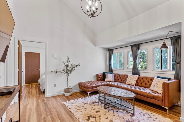 living room featuring high vaulted ceiling, hardwood / wood-style flooring, and an inviting chandelier