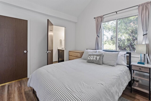 bedroom with dark wood-type flooring, ensuite bathroom, and vaulted ceiling