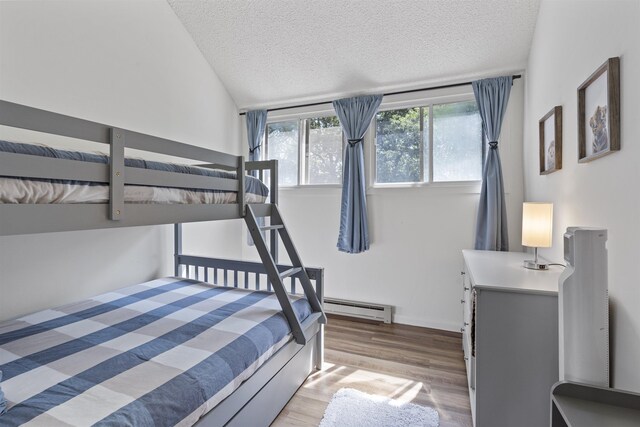 bedroom featuring a textured ceiling, vaulted ceiling, hardwood / wood-style floors, and baseboard heating