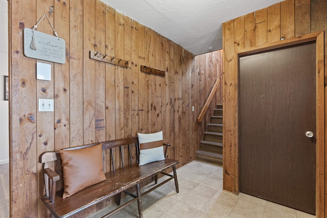 interior space with wood walls, a textured ceiling, and light tile floors